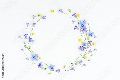 Wreath made of bell flowers, pansy flowers and yellow flowers on white background. Flat lay, top view