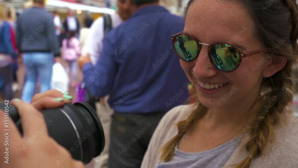Young Woman Wears Reflective Sunglasses, Her Friend Takes A Photo Of Her, At A Marketplace In Amsterdam, Netherlands Young Woman Wears Reflective Sunglasses, Her Friend Takes A Photo Of Her, At A Marketplace In Amsterdam, Netherlands