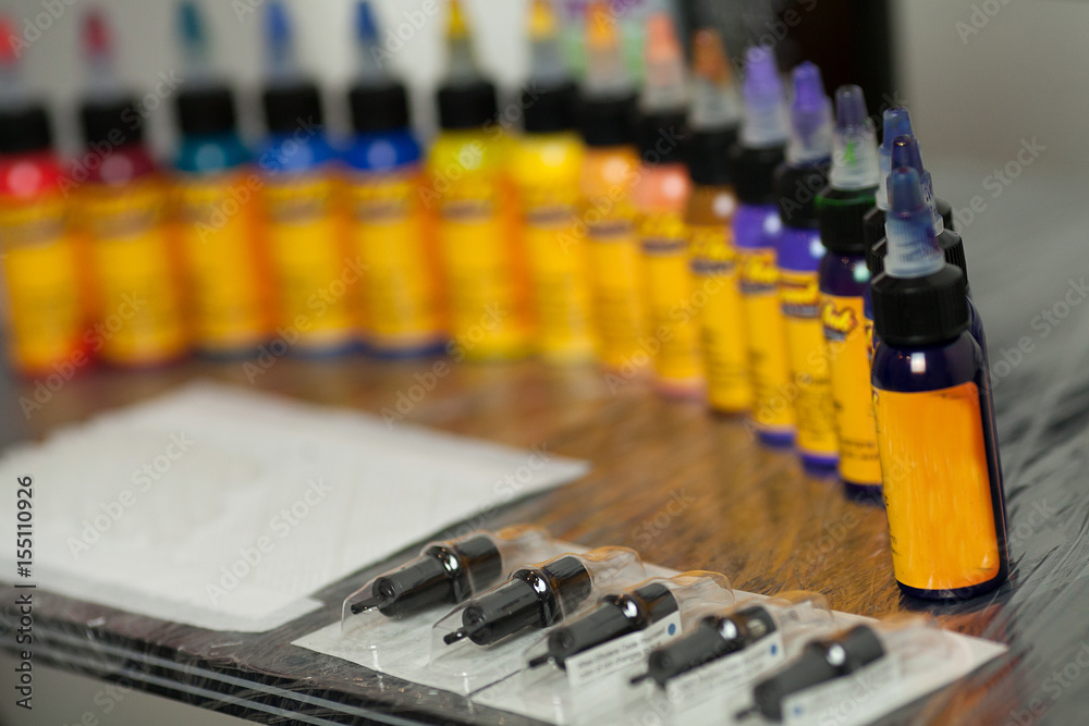 Multiple bottles with colorful inks for tattoo, close up view. Selective focus.