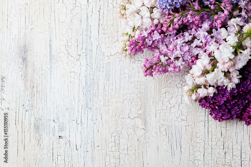 Bunch of lilac flowers on a white crackling effect background. Top view. Copy space.