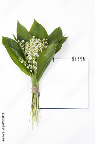 Lilly of the valley flowers and leaves bouquet with sketchpad