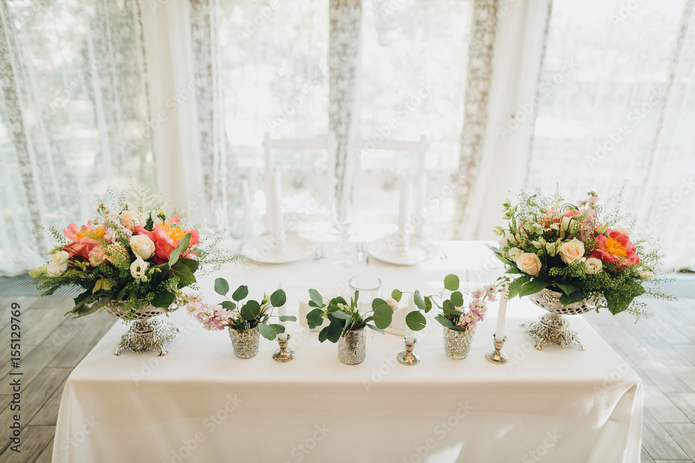 On the festive table in the wedding banquet area there are compositions of flowers, candles, plates, cutlery, napkins On the festive table in the wedding banquet area there are compositions of flowers, candles, plates, cutlery, napkins