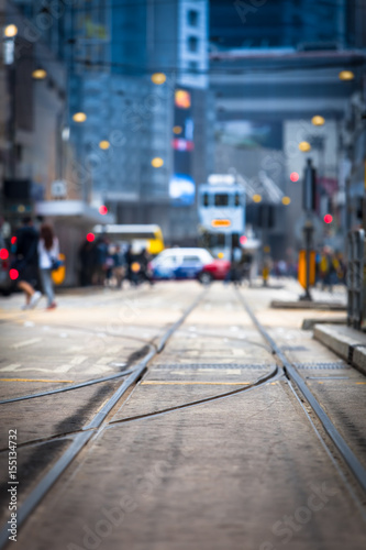 Hong Kong Street View / Streetcar tracks toward blurred urban traffic background with tram, car, unrecognizable people and city buildings at night (copy space)