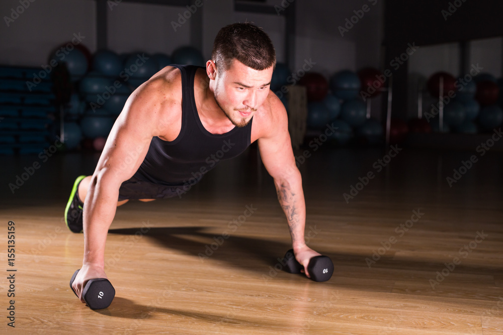 Young Man Athlete Doing Pushups With Dumbbells As Part Of Bodybuilding Training. Young Man Athlete Doing Pushups With Dumbbells As Part Of Bodybuilding Training.