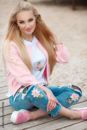 Beautiful autumn woman wear pink jacket posing near the seaa outdoors. Beauty happy long hairl blonde girl smiling at beach. Autumn  style fashion model photo