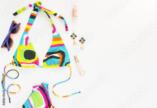 Summer outfit, beach outfit, summer stuff. Geometric abstract pattern swimsuit, bright sunglasses and earrings. Flat lay, top view.