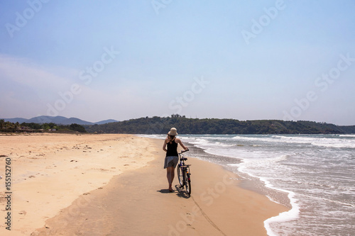 girl with bicycle on a sand shore