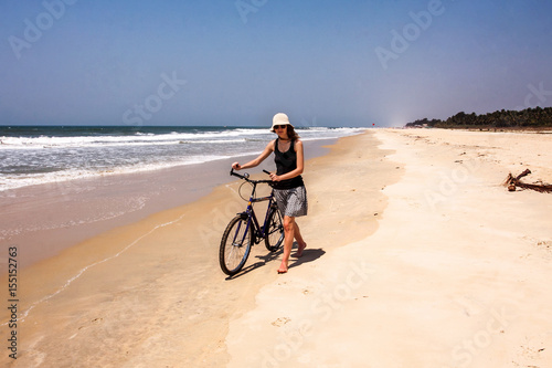 girl with bicycle on a sand shore