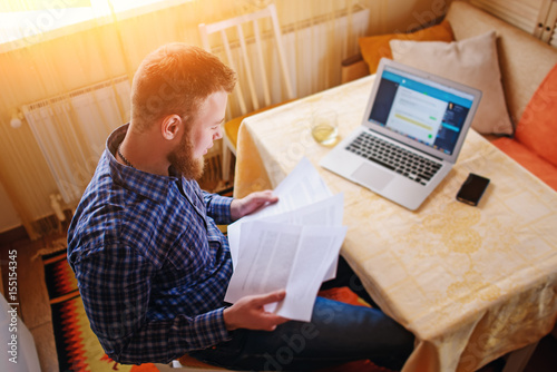 Obraz na płótnie Businessman at home, he is working with a laptop, checking paperwork and bills w salonie