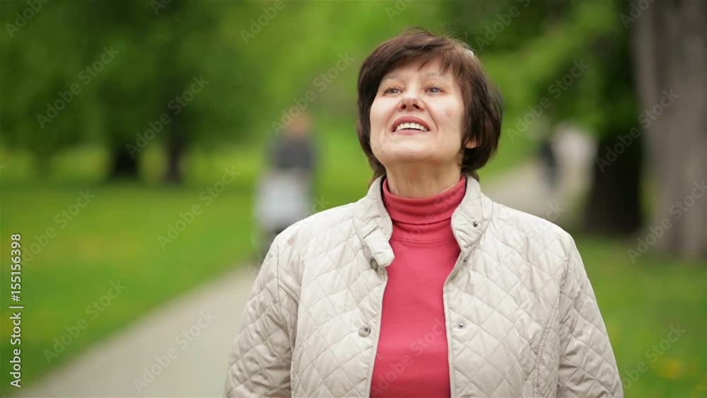Portrait of Beautiful Woman Smiling and Enjoying Spring in the Park. Attractive Brunette Wearing White Jacket and Sunglasses Outdoors. Portrait of Beautiful Woman Smiling and Enjoying Spring in the Park. Attractive Brunette Wearing White Jacket and Sunglasses Outdoors.
