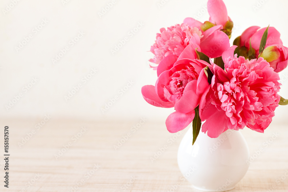 Pink peonies in vase on wood background