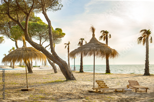 Sandy beach with wooden chaise-longs and umbrellas on the Adriatic Sea coast in Albania. photo