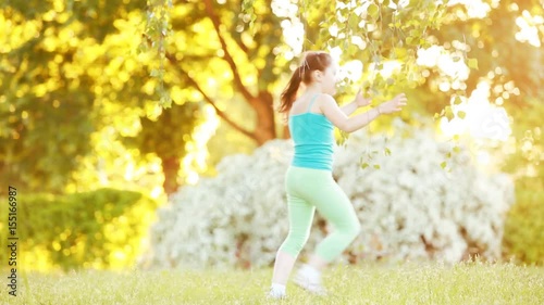 Cute little girl walking under tree in the park at sunshine summer day.
