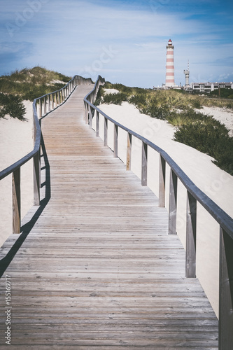 Praia da Barra Portuguese lighthouse on coast  Symbol of city Barra  Surfing beach area Barra  Wooden pier at beach  Wooden bridge for runners  Symbol of Portuguese summer vacation