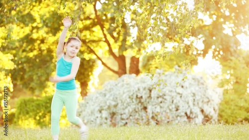 Cute little girl walking under tree in the park at sunshine summer day.