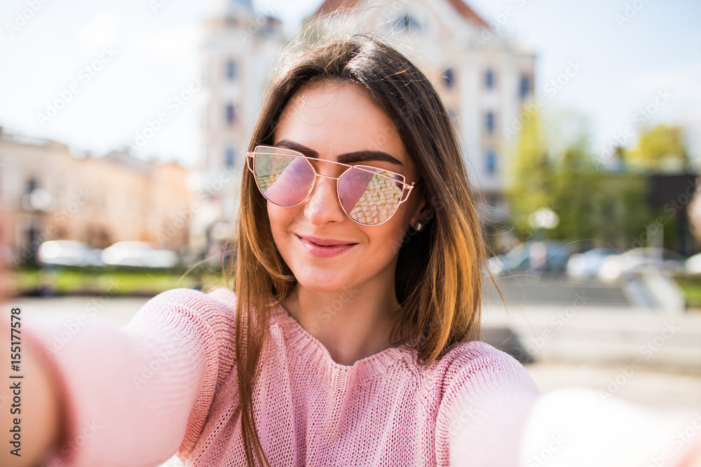 Closeup selfie-portrait student of attractive girl in sunglasses with long hairstyle and smile in city. Closeup selfie-portrait student of attractive girl in sunglasses with long hairstyle and smile in city.