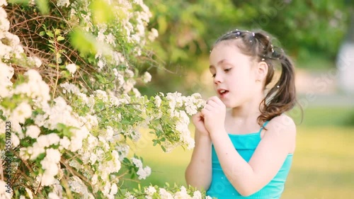 Close-up of little girl enjoys the smell of flowers in the meadow in summer.