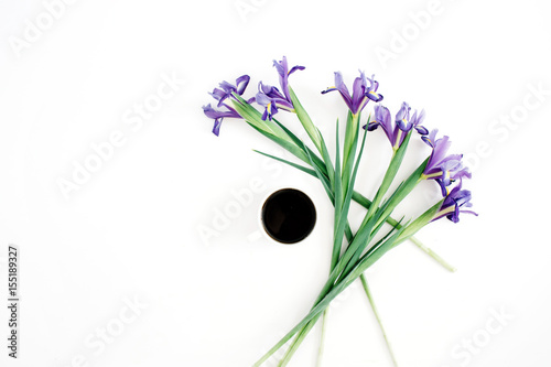 Fototapeta Naklejka Na Ścianę i Meble -  Cup of coffee and purple iris flowers on white background. Flat lay, top view.