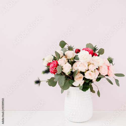 Beautiful flowers bouquet in flowerpot in front of pale pastel pink wall. Floral lifestyle composition.