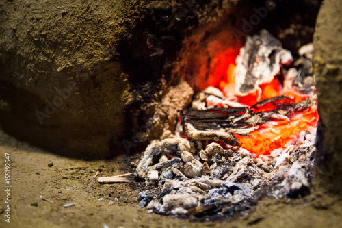 Embers of a dying fire in a wood fired stove made out of mud and clay in a traditional outdoor Sri Lankan kitchen.