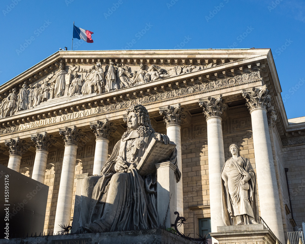 View of the front of the Bourbon Palace in Paris which houses the french National Assembly, with the statue of Francois d'Aguesseau in foreground and the french flag flying in the wind