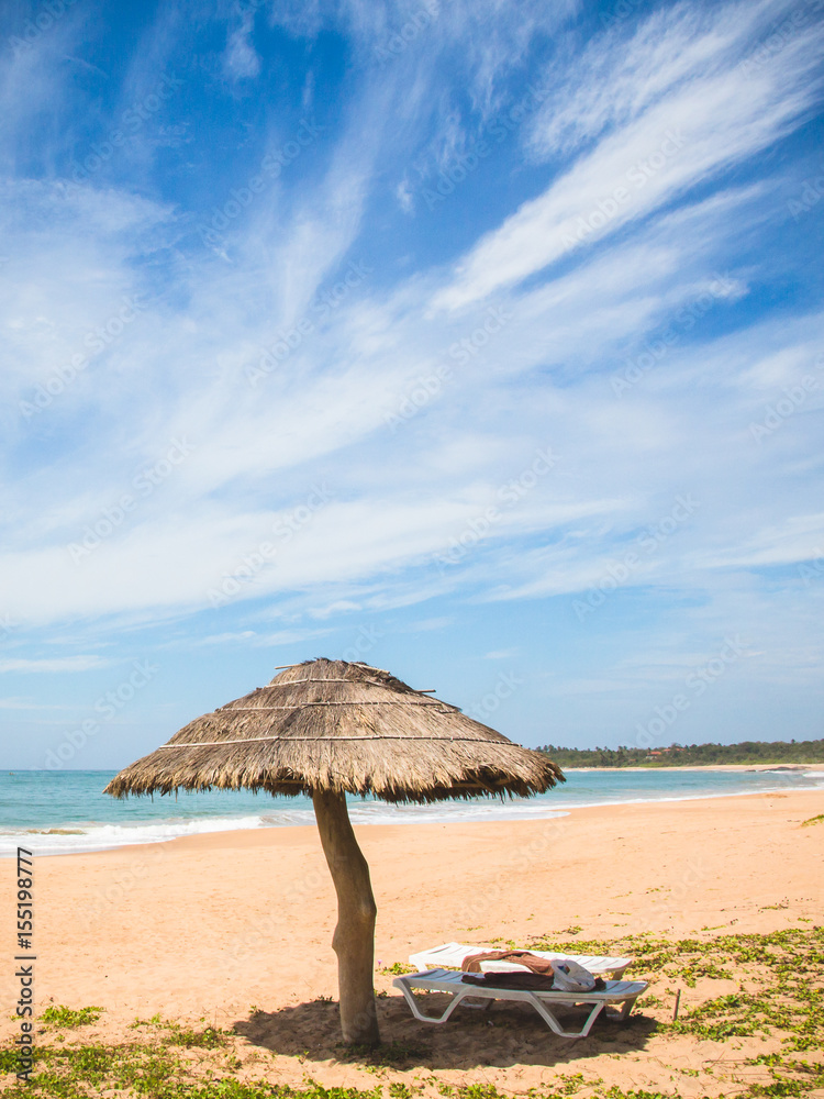A straw umbrella and deckchair on kahandamodara beach, just outside of Tangalle, Sri Lanka.