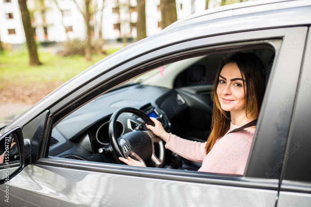 Confident and beautiful young woman in casual wear looking over her shoulder while driving a car Confident and beautiful young woman in casual wear looking over her shoulder while driving a car