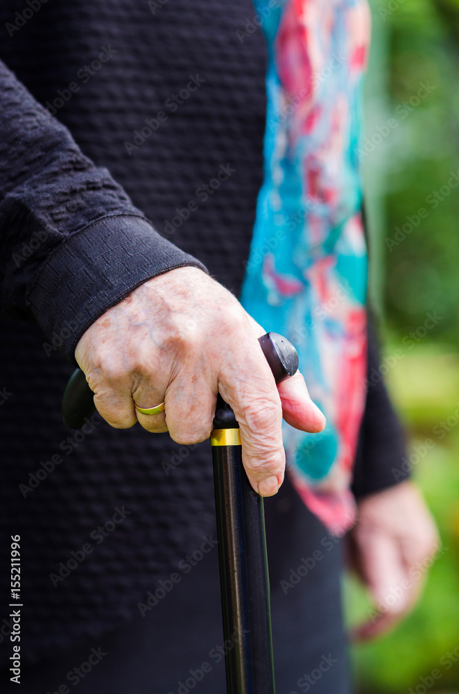 Old elderly woman with scarf walking with stick