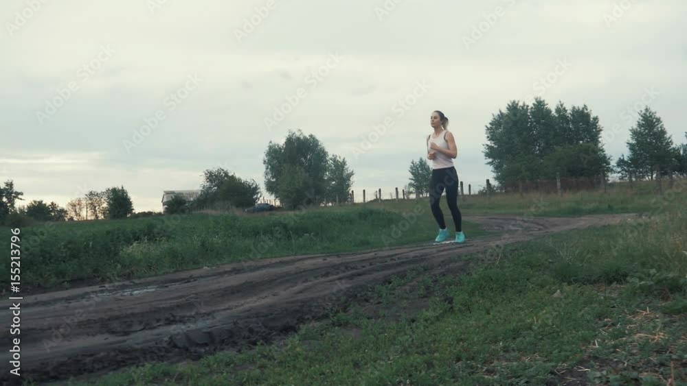 Athletic girl running at road in field. outdoors fitness. Shot with steadicam Athletic girl running at road in field. outdoors fitness. Shot with steadicam