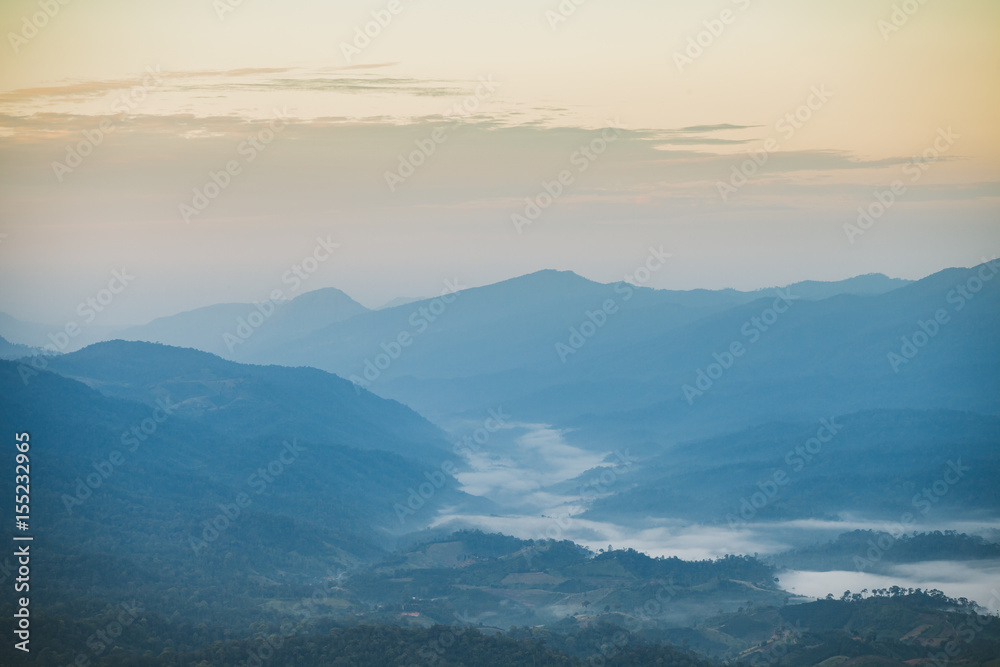 Beautiful autumnal landscape with sunrise over a foggy valley and mountain ranges.