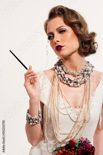 Woman with stylish makeup and retro hairdo holding flowers