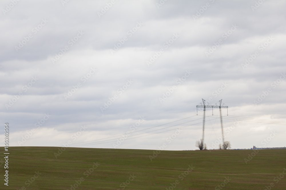 Green field with double high-voltage tower - spring countryside in Russia