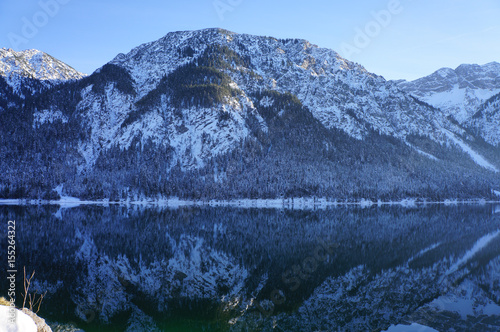 Snow capped mountain reflections in Plan See lake, Austria