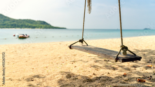 The beach swing is made of wood attached to the coconut trees No body