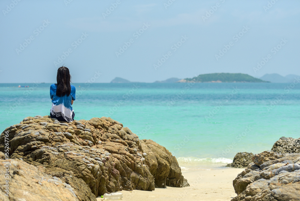 Lonely girl sitting at the beach with sea. Thoughtful and loving. Young girl sitting on the beach relaxing. In the background the waves of the Mediterranean Sea