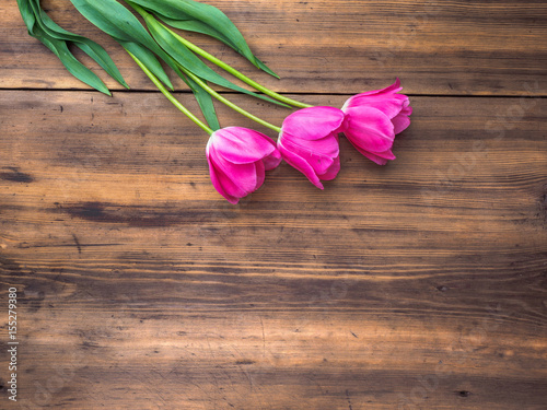 Fototapeta Naklejka Na Ścianę i Meble -  Pink tulips, floral arrangement on wooden background from old boards and a space for messages. Background for Mother's Day, 8 March and other greeting cards for lovely women. Soft focus, top view.