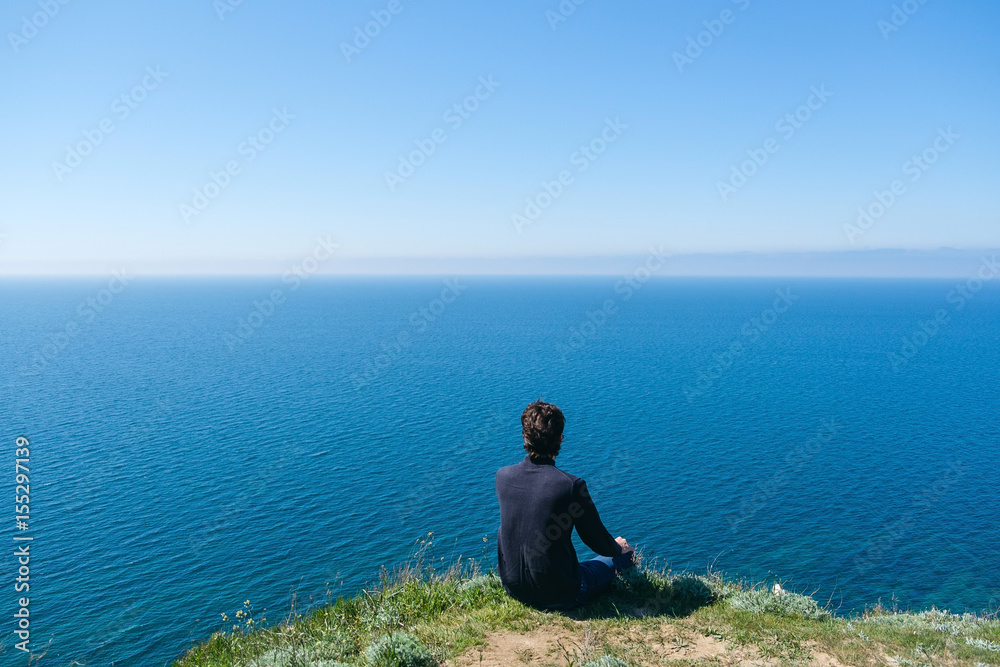 Man sitting on edge of cliff at edge