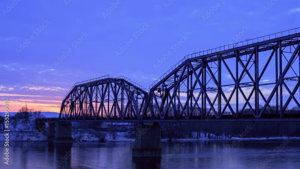 Time lapse of railway bridge over the river at dawn with a mountain forest and traffic highway in the background. Time lapse of railway bridge over the river at dawn with a mountain forest and traffic highway in the background.