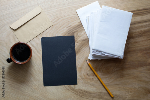 A sheet of dark paper  envelope  cup of coffee on a wooden texture