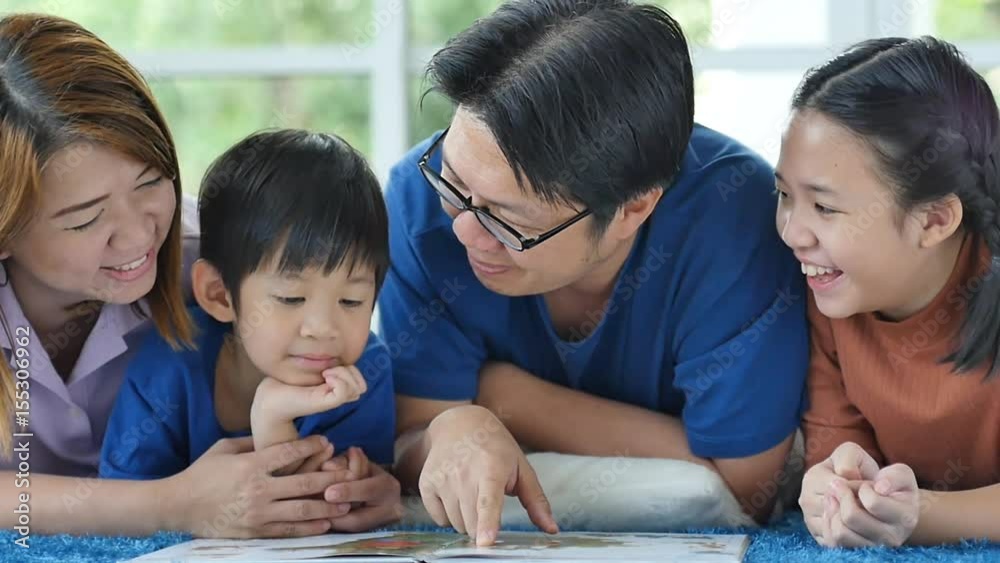 Happy Asian family reading book at home Happy Asian family reading book at home