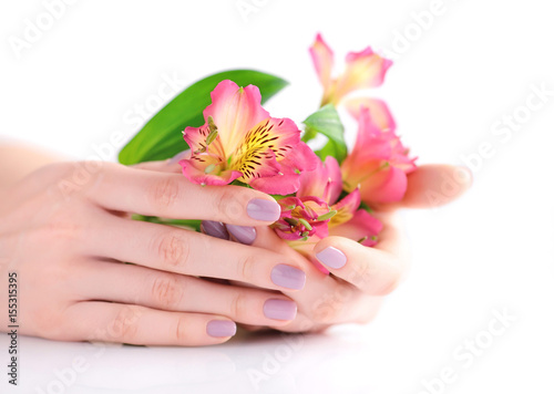 Hands of a woman with pink manicure on nails and flowers alstroemeria on a white background