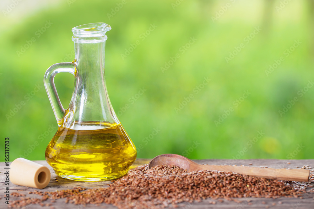 flax seeds and linseed oil in a glass jug on a wooden table flax seeds and linseed oil in a glass jug on a wooden table