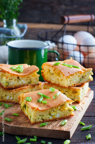A jellied pie with green onions and eggs on a wooden board, selective focus