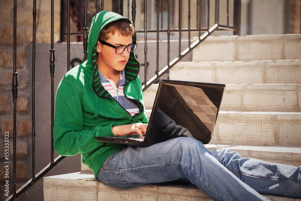 Young man using laptop on the steps Young man using laptop on the steps