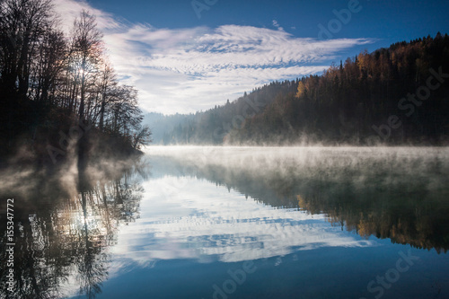 Mountain lake in autumn. Fog above water early in the morning.