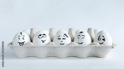 Eggs with funny faces in the package on a white background. Easter Concept Photo. Faces on the eggs