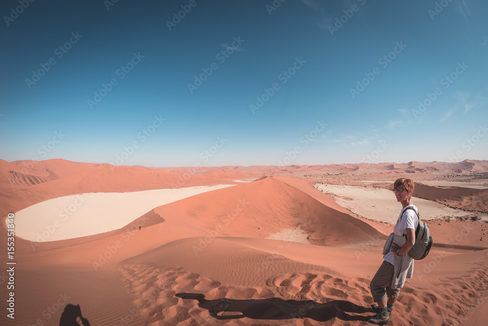 Tourist walking on the scenic dunes of Sossusvlei, Namib desert, Namib Naukluft National Park, Namibia. Afternoon light. Adventure and exploration in Africa. Tourist walking on the scenic dunes of Sossusvlei, Namib desert, Namib Naukluft National Park, Namibia. Afternoon light. Adventure and exploration in Africa.