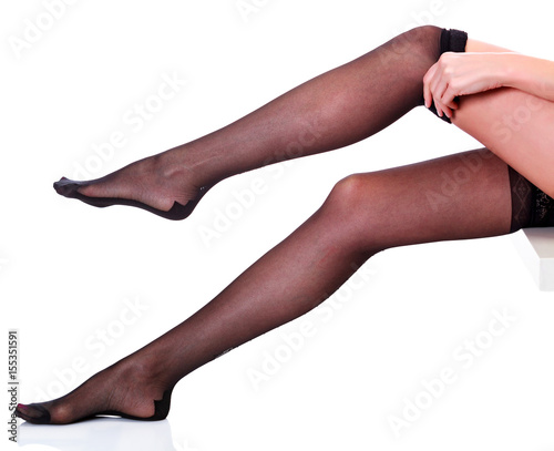 Woman puts on stockings on her beautiful long legs  isolated on white background