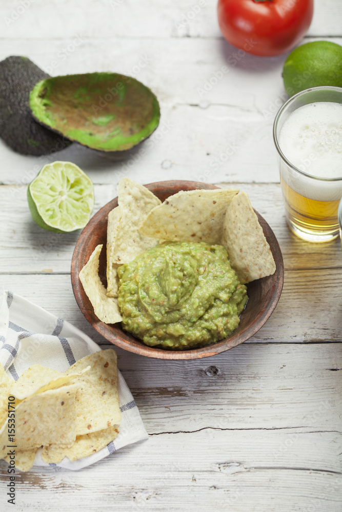 Homemade guacamole with corn nachos and a glasses of beer