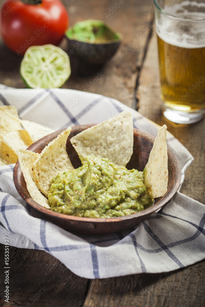 Homemade guacamole with corn nachos and a glasses of beer Homemade guacamole with corn nachos and a glasses of beer